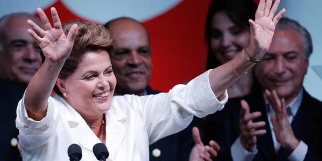 Brazil's President Dilma Rousseff, raises her arms to acknowledge the crowd during her acceptance speech at a press conference in a hotel in Brasilia, Brazil, Sunday, Oct. 26, 2014. Official results showed Sunday that President Rousseff defeated opposition candidate Aecio Neves of the Brazilian Social Democracy Party, and was re-elected Brazil's president. (AP Photo/Eraldo Peres)