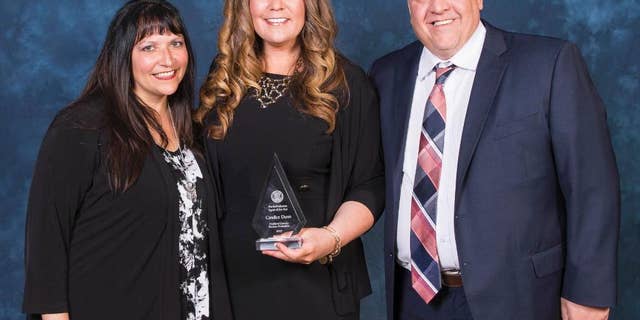 In this Tuesday, March 9, 2017 photo, provided by the Michigan Department of Corrections, Candice Dunn, center, stands with employees Heather Wayne and Brock Dietrich after receiving the state's parole/probation agent of the year award in East Lansing, Mich. Dunn was one of five people killed in a car crash Tuesday, May 9, in Livingston County. (Michigan Department of Corrections via AP)