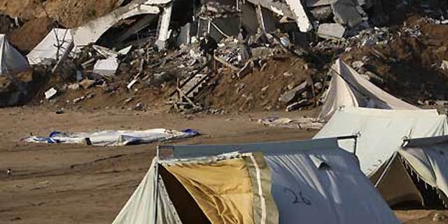 Feb. 21: A Palestinian family, background, walk next to collapsed tents that housed people who had lost their homes in Israel's incursion into Gaza.