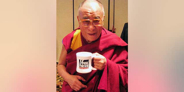 His Holiness the Dalai Lama poses with his FOX News mug after an interview.