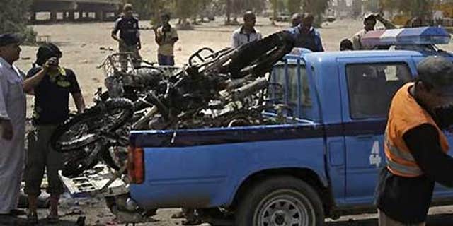 June 26: Iraqis load destroyed motorcycles in Baghdad, Iraq, after a booby-trapped motorcycle exploded in a crowded bazaar in Baghdad.