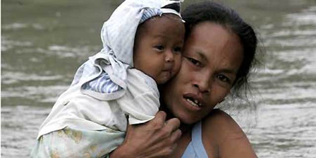 Oct. 2: A mother cuddles her child while wading through floodwaters in Taytay township, Rizal province east of Manila.