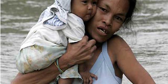 Oct. 2: A mother cuddles her child while wading through floodwaters in Taytay township, Rizal province east of Manila.