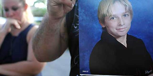 Oct. 13: Danny Martinez, unseen, holds a photo of his brother-in-law, Michael Brewer, 15, who was set on fire.