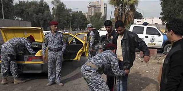 Dec. 14: Iraqi policemen search a man and his car at checkpoint in central Baghdad, Iraq.