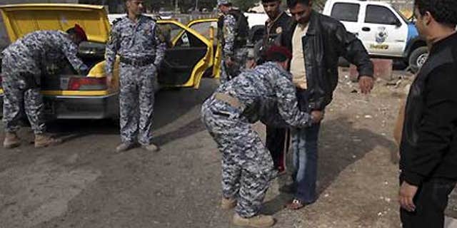 Dec. 14: Iraqi policemen search a man and his car at checkpoint in central Baghdad, Iraq.