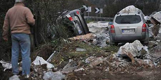 Dec. 17: A man looks at damaged cars next to huge fallen rocks on the main highway south of Thessaloniki, Greece.