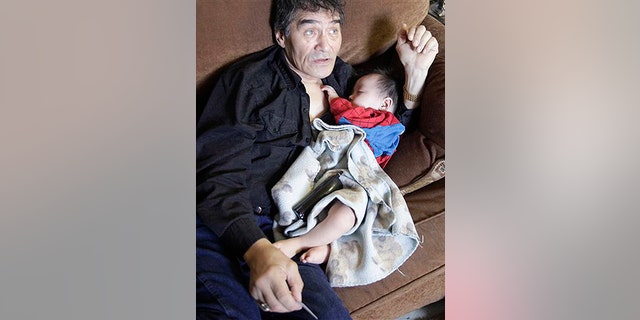 In this Aug. 8, 2009 photo, Henry Nasogaluak Jr. sleeps in the arms of his father Henry Nasogaluak in Tuktoyaktuk, in the Northwest Territories, Canada. Henry Jr. slept in his father's arms as the hunter pondered the future of the boy born last Arctic winter, in the depths of a polar bear season he'd rather forget. "It's too late to be a hunter. I don't want him to do that," Henry Nasogaluak said of his son. "It's a hard life, and it got harder with the ban by the United States." (AP Photo/Rick Bowmer)