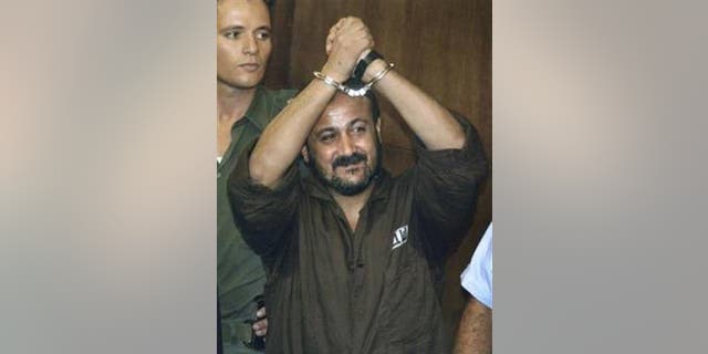 In this Aug. 14, 2002 file photo Marwan Barghouti raises his handcuffed hands in the air on the opening day of his trial at Tel Aviv's District Court