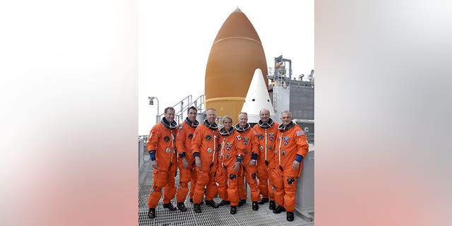 The STS-127 pose next to the top of Endeavour's orange fuel tank and twin solid-fuel rocket boosters.