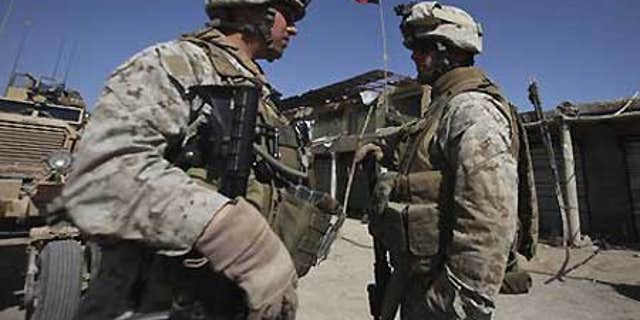 Feb. 17: U.S. Marines with NATO forces talk as newly raised Afghan flag is seen in the background at a deserted market of Marjah, Afghanistan.