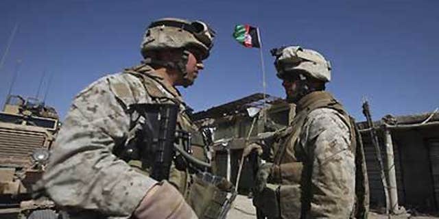 Feb. 17: U.S. Marines with NATO forces talk as newly raised Afghan flag is seen in the background at a deserted market of Marjah, Afghanistan.