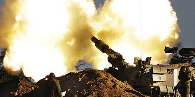 Jan. 6: Israeli Army soldiers take cover as a mobile artillery piece fires towards targets in the southern Gaza Strip.