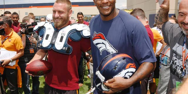 AS Roma player Daniele De Rossi, left, tries on the shoulder pads of Denver Broncos tight end Julius Thomas as members of the Italian soccer team meet Broncos players after the Broncos' NFL football training camp session in Englewood, Colo., on Friday, July 25, 2014. AS Roma is in Denver to face Manchester United on Saturday. (AP Photo)