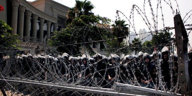 FILE - In this Thursday, June 14, 2012 file photo, Egyptian soldiers stand guard during a protest in front the Supreme Constitutional Court, Egypt's highest court, background, in Cairo, Egypt. Islamists and former members of the military have pushed back Sunday against the decision by Egypt’s Supreme Constitutional Court which states that barring members of the armed forces and police from voting goes against the country’s first constitution after the ouster of longtime authoritarian leader Hosni Mubarak. (AP Photo/Nasser Nasser, File)