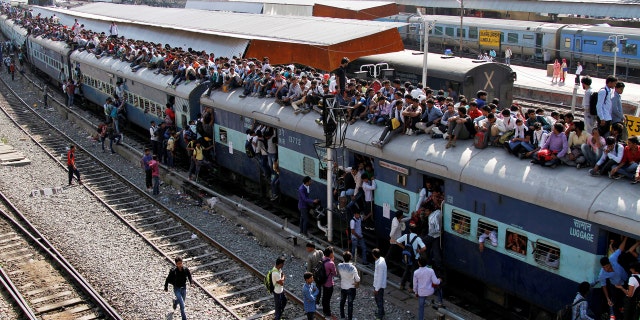 Passengers board an overcrowded train at a railway station in Ajmer, India.