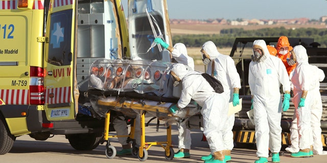 In this photo provided by the Spanish Defense Ministry, aid workers and doctors transfer Miguel Pajares, a Spanish priest who was infected with the Ebola virus while working in Liberia, from a plane to an ambulance as he leaves a military airbase, near Madrid, Spain. Teresa Romero, 44, a nursing assistant, reportedly became infected with Ebola while caring for Pajares.