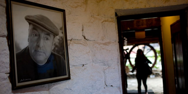 In this April 26, 2015 photo, a framed photo of Nobel Prize-winning poet Pablo Neruda hangs on a wall, as a tourist enters his favorite home in Isla Negra, Chile. (AP Photo/Natacha Pisarenko)