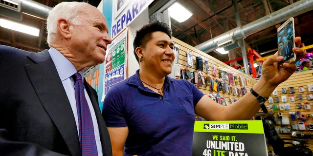 U.S. Sen. John McCain, R-Ariz., poses for a selfie with shop owner Aron Mercado at the El Mercado De Los Cielos mall prior to announcing the launch of the âUnidos Con McCainâ Hispanic coalition, Thursday, Oct. 15, 2015, in Phoenix. McCain is trying to woo Hispanic voters to his re-election effort by putting together a coalition of Latino business leaders who back the Republican. (AP Photo/Matt York)