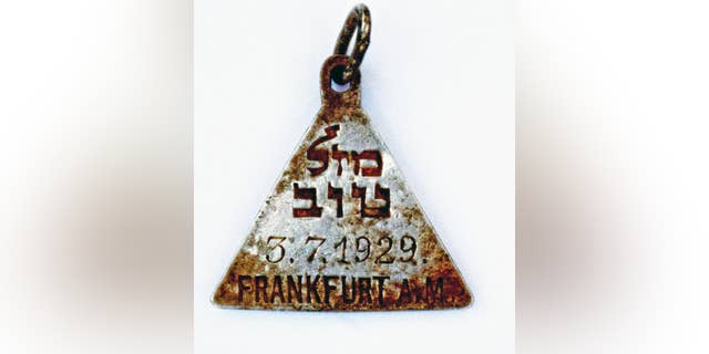 This undated photograph released by the Israel Antiquities Authority shows a pendant that appears identical to one belonging to Anne Frank, Israel's Yad Vashem Holocaust memorial said Sunday. Yad Vashem says it has ascertained the pendant belonged to Karoline Cohn _ a Jewish girl who perished at Sobibor and may have been connected to the famous diarist. Both were born in Frankfurt in 1929 and historians have found no other pendants like theirs. The triangular piece found has the words "Mazal Tov" written in Hebrew on one side along with Cohn's date of birth and the Hebrew letter "heh," an initial for God, as well as three Stars of David on the other. (Yoram Haimi, Israel Antiquities Authority via AP)