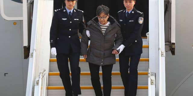 Yang Xiuzhu is escorted down a plane upon arriving at the Beijing Capital International Airport.
