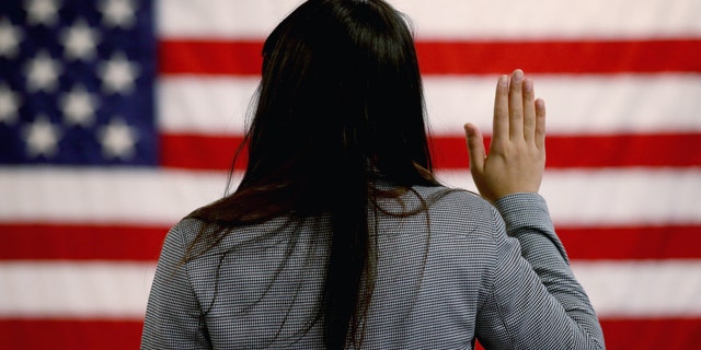 NEWARK, NJ - JANUARY 28: An woman takes the oath of allegiance during a naturalization ceremony at the at district office of the U.S. Citizenship and Immigration Services (USCIS) on January 28, 2013 in Newark, New Jersey. Some 38,000 immigrants became U.S. citizens at the Newark office alone in 2012. (Photo by John Moore/Getty Images)