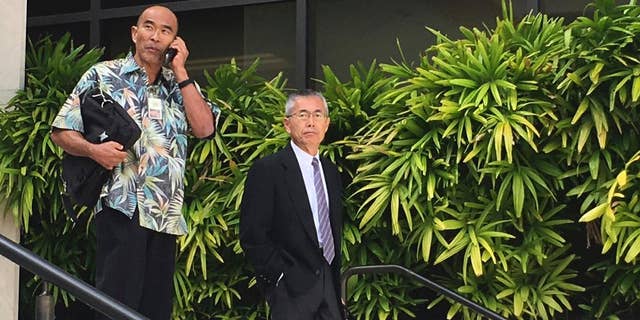 FILE- In this Nov. 1, 2016, file photo, Kauai Community Correctional Center Warden Neal Wagatsuma, left, uses a cellphone while walking out of U.S. District Court in Honolulu with Hawaii Deputy Attorney General Nelson Nabeta. After a week of deliberations, the jury on Tuesday, Dec. 20, voted unanimously in favor of defendants Neal Wagatsuma and the state of Hawaii in a lawsuit brought by a former jail social worker. (AP Photo/Jennifer Sinco Kelleher, File)