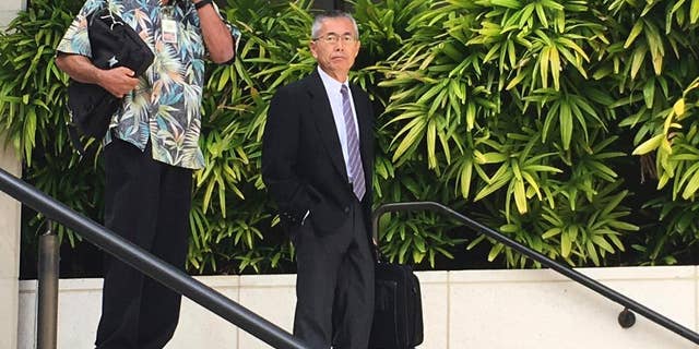 FILE- In this Nov. 1, 2016, file photo, Kauai Community Correctional Center Warden Neal Wagatsuma, left, uses a cellphone while walking out of U.S. District Court in Honolulu with Hawaii Deputy Attorney General Nelson Nabeta. After a week of deliberations, the jury on Tuesday, Dec. 20, voted unanimously in favor of defendants Neal Wagatsuma and the state of Hawaii in a lawsuit brought by a former jail social worker. (AP Photo/Jennifer Sinco Kelleher, File)