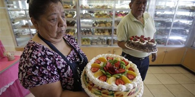 In this July 31, 2014, photo, Concepcion Flores, owner of Panaderia Flores, holds a gelatina cake on Salt Lake Citys west side. Panaderia Flores offers sweet breads, pineapple or pumpkin empanadas and tamales. (AP Photo/Rick Bowmer)