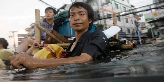 Oct. 27, 2011: A Thai man wades along chest-deep floodwaters in the outskirts of Bangkok, Thailand.