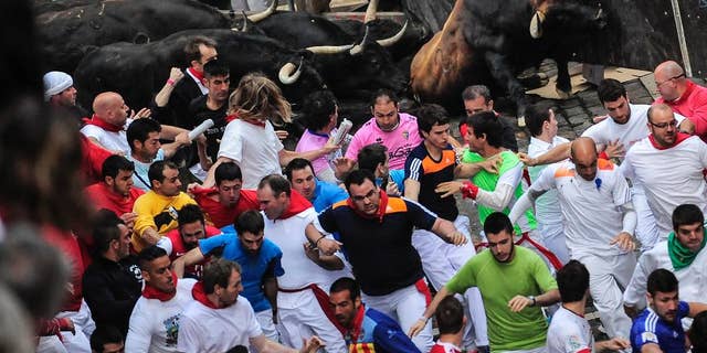 Revelers run ahead of ''Jandilla'' fighting bulls on Estafeta corner on the way to the bull ring, during the running of the bulls, at the San Fermin festival, in Pamplona, Spain, Friday, July 11, 2014. Revelers from around the world arrive to Pamplona every year to take part in some of the eight days of the running of the bulls. (AP Photo/Alvaro Barrientos)
