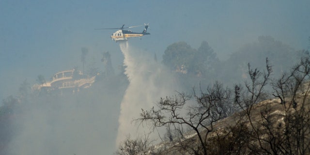 A helicopter drops water on hotspots left by the Skirball fire near the Bel Air neighborhood on the west side of Los Angeles, California, U.S., December 6, 2017.