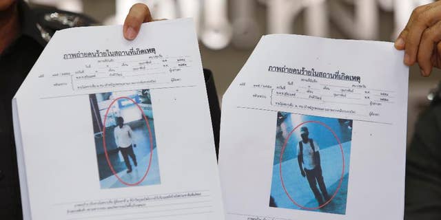 Photos of two suspects believed linked to a pair of small bomb blasts outside a luxury shopping mall in Bangkok over the weekend, are shown by police officers at the police headquarters in Bangkok, Thailand Wednesday, Feb. 4, 2015. Authorities in Thailand have issued arrest warrants for the two suspects. The blurry images of the suspects, described as "Asian-looking" by a police spokesman, were captured on closed-circuit camera footage close to where the homemade pipe bombs detonated and wounded one person. (AP Photo/Sakchai Lalit)
