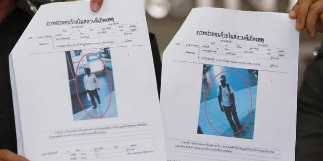 Photos of two suspects believed linked to a pair of small bomb blasts outside a luxury shopping mall in Bangkok over the weekend, are shown by police officers at the police headquarters in Bangkok, Thailand Wednesday, Feb. 4, 2015. Authorities in Thailand have issued arrest warrants for the two suspects. The blurry images of the suspects, described as "Asian-looking" by a police spokesman, were captured on closed-circuit camera footage close to where the homemade pipe bombs detonated and wounded one person. (AP Photo/Sakchai Lalit)