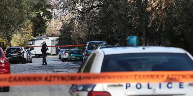 A policeman secures a street where police conduct an investigation at a suburb of Athens, Thursday, Jan. 5, 2017. Greek police say they have recaptured a convicted far-left militant wanted for more than four years after she absconded during her trial on domestic terrorism charges.