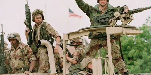 FILE - In a Dec. 10, 1992 file photo, a U.S. Marine gives the thumbs up as a truck load of troops arrive at the reopened U.S. Embassy in Mogadishu, Somalia.  According to the U.S. Africa Command on Friday April 14, 2017,  the U.S. military is sending dozens of regular troops to Somalia to train Somali soldiers in the largest such deployment to the Horn of Africa country in roughly two decades.   (AP Photo/Denis Pauqin, File)