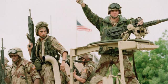 FILE - In a Dec. 10, 1992 file photo, a U.S. Marine gives the thumbs up as a truck load of troops arrive at the reopened U.S. Embassy in Mogadishu, Somalia. According to the U.S. Africa Command on Friday April 14, 2017, the U.S. military is sending dozens of regular troops to Somalia to train Somali soldiers in the largest such deployment to the Horn of Africa country in roughly two decades. (AP Photo/Denis Pauqin, File)