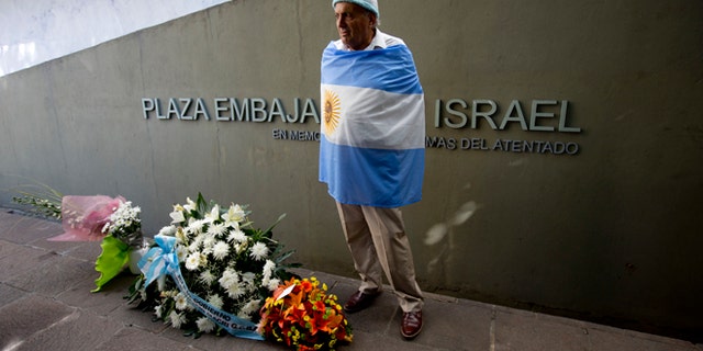 Juan Pulvirenti stands next to several floral arrangements placed on the site where the Israeli Embassy used to be during an act to commemorate the 23rd anniversary of the bomb attack that destroyed the building killing 22 people, in Buenos Aires, Argentina, Tuesday, March 17, 2015. (AP Photo/Natacha Pisarenko)