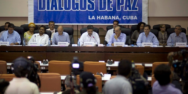 FILE - In this May 16, 2014 file photo, negotiators from the Revolutionary Armed Forces of Colombia (FARC), left, and Colombia's government, right, give a press conference under a sign that reads in Spanish "Peace Talks" in Havana, Cuba. Colombia's government has rebuffed a unilateral truce declared on Wednesday, Dec. 18, 2014 by the country's largest rebel group, saying conditions demanded by the guerrillasâ are unacceptable until a peace deal is reached. Sitting at the table, from left, are chief of the western bloc of the FARC Pablo Catatumbo, FARC chief negotiator Ivan Marquez, Norwegian guarantor Dag Nylander, Cuban guarantor Rodolfo Benitez Verson, head of Colombia's government team Humberto de la Calle, government negotiator Sergio Jaramillo, and government negotiator Gen. Jorge Mora. (AP Photo/Ramon Espinosa, File)