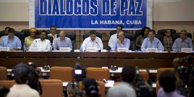 FILE - In this May 16, 2014 file photo, negotiators from the Revolutionary Armed Forces of Colombia (FARC), left, and Colombia's government, right, give a press conference under a sign that reads in Spanish "Peace Talks" in Havana, Cuba. Colombia's government has rebuffed a unilateral truce declared on Wednesday, Dec. 18, 2014 by the country's largest rebel group, saying conditions demanded by the guerrillasâ are unacceptable until a peace deal is reached. Sitting at the table, from left, are chief of the western bloc of the FARC Pablo Catatumbo, FARC chief negotiator Ivan Marquez, Norwegian guarantor Dag Nylander, Cuban guarantor Rodolfo Benitez Verson, head of Colombia's government team Humberto de la Calle, government negotiator Sergio Jaramillo, and government negotiator Gen. Jorge Mora. (AP Photo/Ramon Espinosa, File)