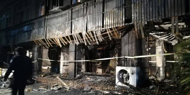 In this photo released by Xinhua News Agency, a man walks past the Zuxintang Foot Massage Parlor damaged by a fire in Tiantai County, east China's Zhejiang Province, Monday, Feb. 6, 2017. The fire at the massage parlor on Sunday killed and injured dozens of people, state media reported. (Wang Junlu/Xinhua via AP)