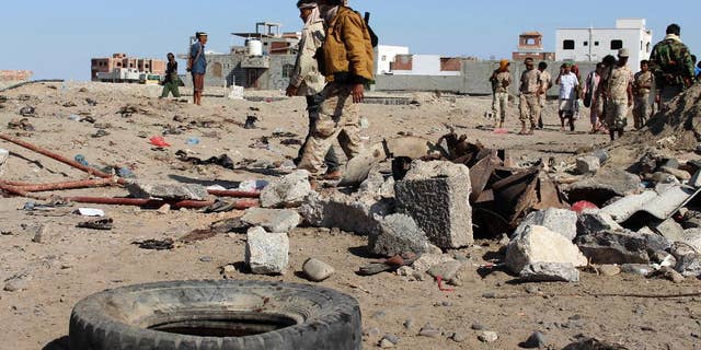 FILE - In this Sunday, Dec. 18, 2016 file photo, soldiers gather the site of a suicide bomb at a base in the southern city of Aden, Yemen. On a rocky hill overlooking the Arabian Sea in the southern city of Aden sits the heavily fortified palace of Yemen’s internationally recognized president. It’s one of the few safe places in the country for him and his government, protected by troops at the gates and artilleries and truck-mounted machine guns in the surrounding mountains while naval forces guard him from the sea. (AP Photo/Wael Qubady, File)