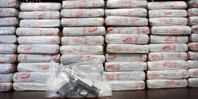 A firearm and 154 pounds of heroin worth at least $50 million are displayed by DEA, Tuesday, May 19, 2015 in New York.