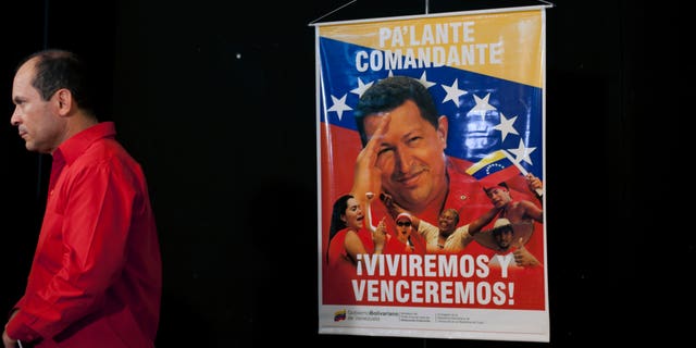 A poster of Venezuela's President Hugo Chavez that reads "Move forward commander, we will live and overcome" hangs as Venezuela's ambassador to Cuba Edgardo Antonio Ramirez stands by after a press conference by Cuban artists and intellectuals to show support for Chavez in Havana, Cuba, Monday, Jan. 7, 2013. Chavez hasn't spoken or appeared publicly since his Dec. 11 operation in Cuba, his fourth surgery for an undisclosed type of pelvic cancer. Speculation about the leader's condition has grown since the operation. (AP Photo/Ramon Espinosa)