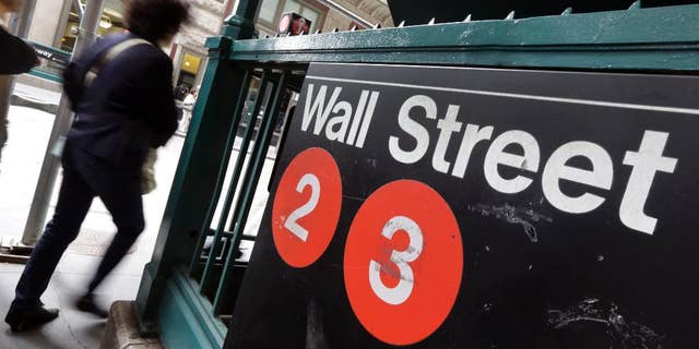 FILE - In this Oct. 2, 2014 file photo, people pass a Wall Street subway stop, in New York's Financial District. U.S. stocks moved lower in early trading Tuesday, March 31, 2015, erasing some gains from the day before. (AP Photo/Richard Drew, File)