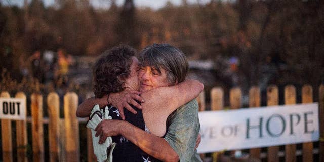 Sharon Dawson, right, who lost her home in a wildfire, embraces a friend while visiting her Middletown, Calif., property on Monday, Sept. 21, 2015. Gov. Jerry Brown requested a presidential disaster declaration on Monday, noting that more than 1,000 homes had been confirmed destroyed, with the number likely to go higher as assessment continues. (AP Photo/Noah Berger)