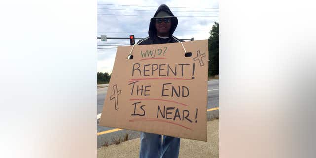 Sept. 21, 2015: Officer Anthony McKnight poses undercover in Somersworth, N.H., with a sign, intending to catch violators of the state’s ban on the use of hand-held phones or electronic devices while driving.
