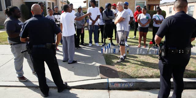 Oct. 2, 2016: Los Angeles Police officers speak to neighbors and members of the community gathered around a makeshift memorial outside a residence.