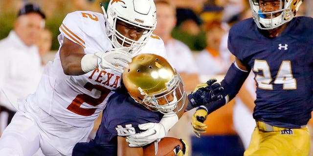 SOUTH BEND, IN - SEPTEMBER 05: Kris Boyd #2 of the Texas Longhorns tackles and dislodges the helmet of Jaylon Smith #9 of the Notre Dame Fighting Irish during the fourth quarter at Notre Dame Stadium on September 5, 2015 in South Bend, Indiana. The Notre Dame Fighting Irish won 38-3. (Photo by Jon Durr/Getty Images)