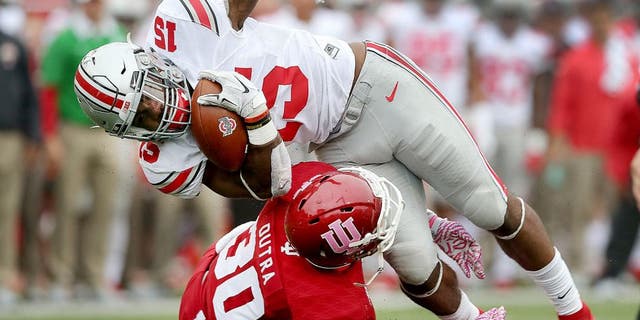 Oct 3, 2015; Bloomington, IN, USA; Ohio State Buckeyes running back Ezekiel Elliott (15) is stopped by Indiana Hoosiers defensive back Chase Dutra (30) in the first half of their game at Memorial Stadium. Mandatory Credit: Matt Kryger-USA TODAY Sports